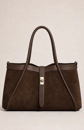 A dark brown suede tote bag with dark brown leather trim and handles, featuring a central gold-tone turn-lock clasp, photographed against a neutral light beige background.