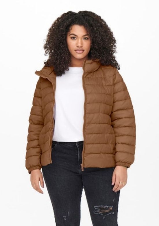 A curly haired woman is wearing an Only Carmakoma jacket in brown.