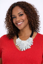 Woman wearing a red top and white necklace with a plain background