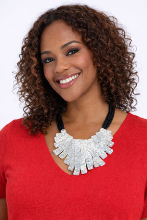 Woman wearing a red top and white necklace with a plain background