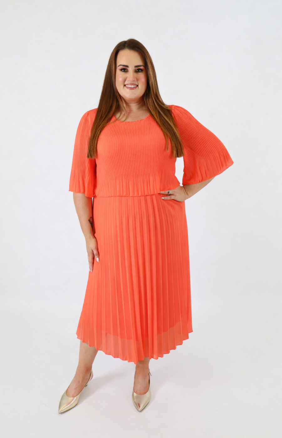 Woman wearing a bright orange dress with a plain background