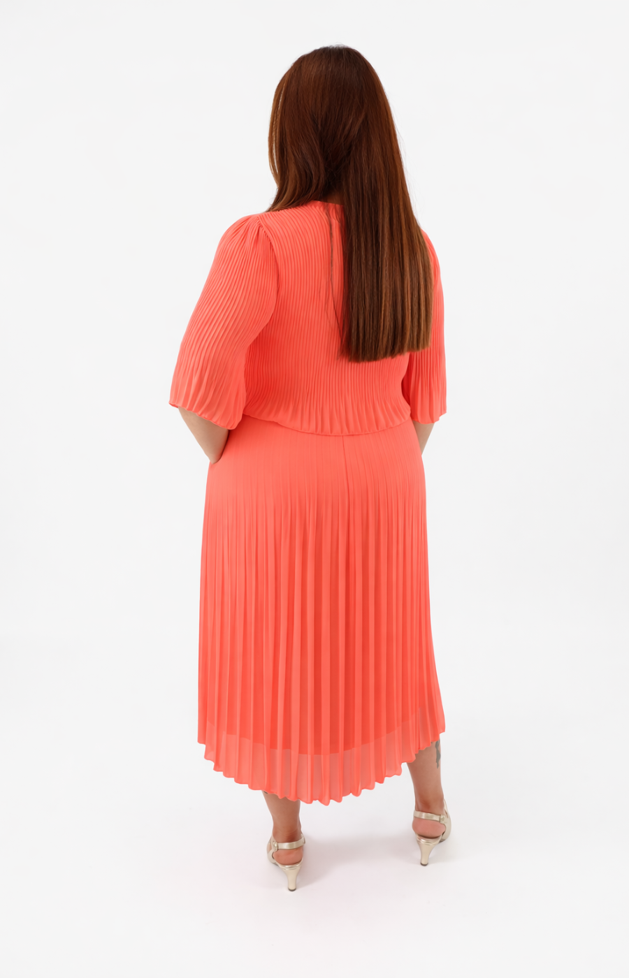 Woman wearing a coral dress with puffed sleeves on a white background