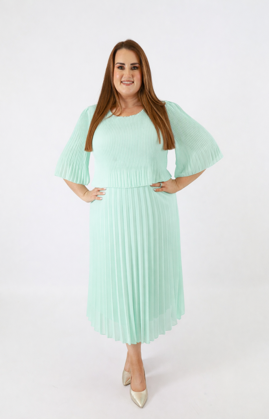 Woman wearing a light green pleated dress on a white background