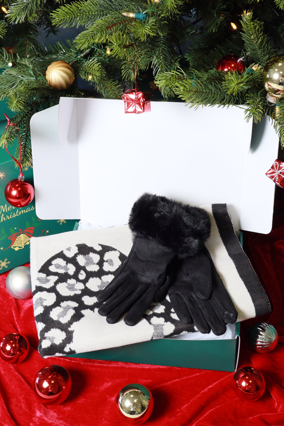 Black gloves with white pattern on a white box, surrounded by Christmas decorations.