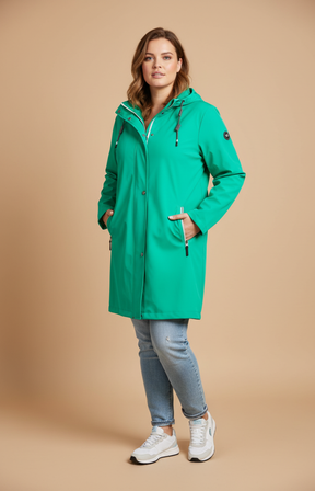 A woman wearing a green rain jacket on cream background