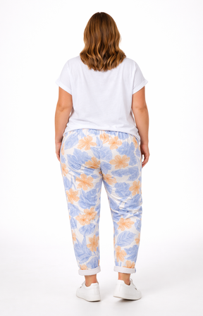 Person wearing a white t-shirt and colorful floral pants on a white background