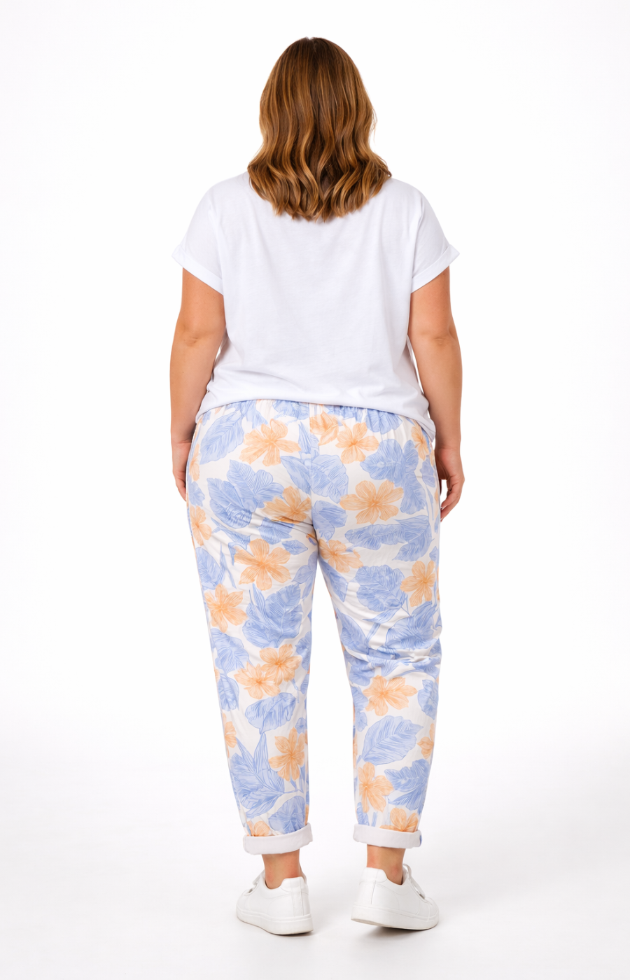 Person wearing a white t-shirt and colorful floral pants on a white background