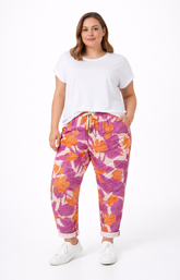 Woman wearing a white t-shirt and colorful floral pants on a white background