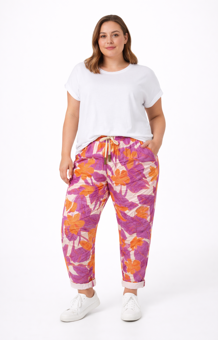 Woman wearing a white t-shirt and colorful floral pants on a white background