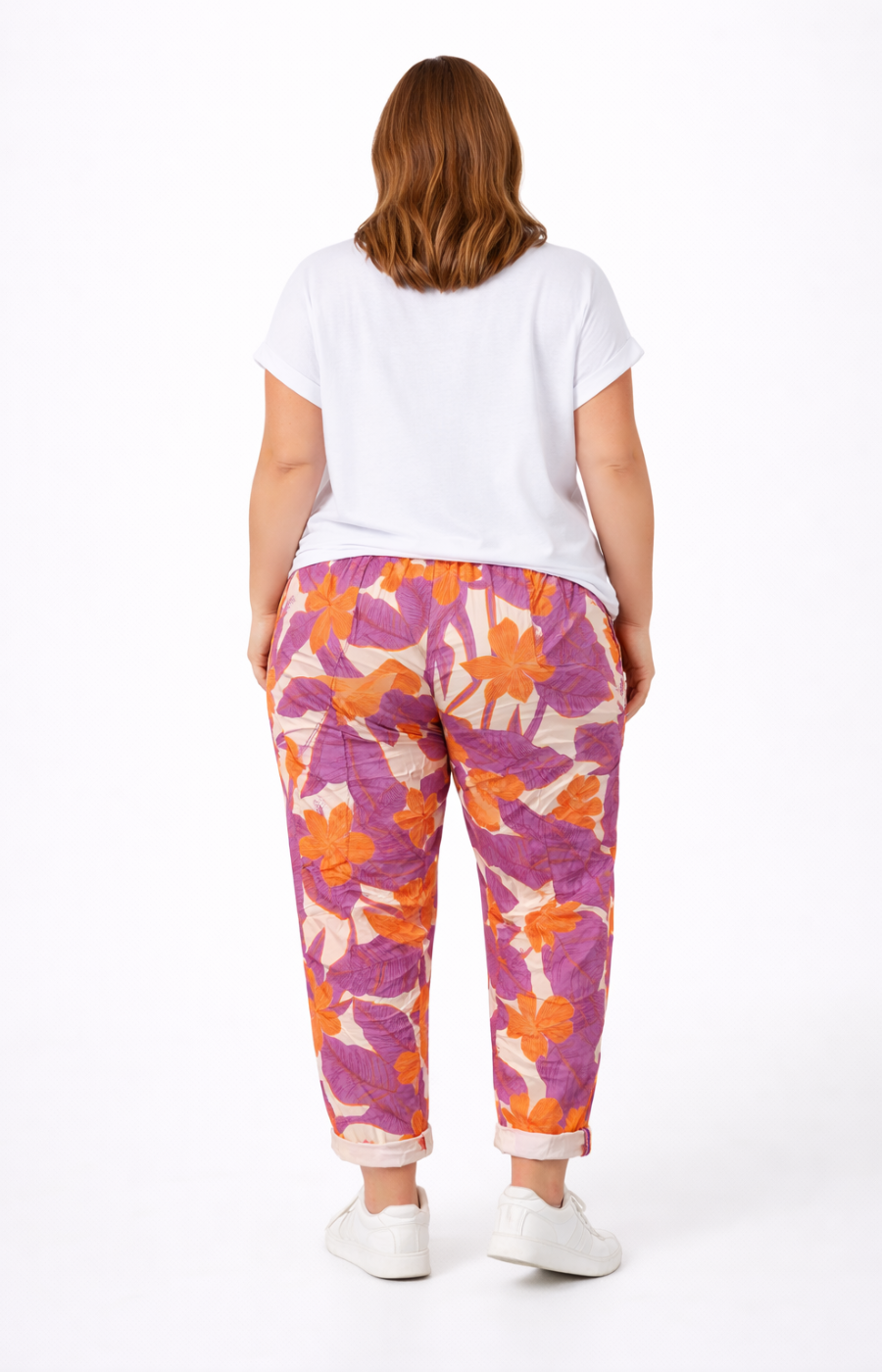 Person wearing a white t-shirt and colorful floral pants on a white background