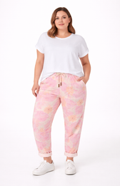 Woman wearing a white t-shirt and pink floral jogger pants on a white background