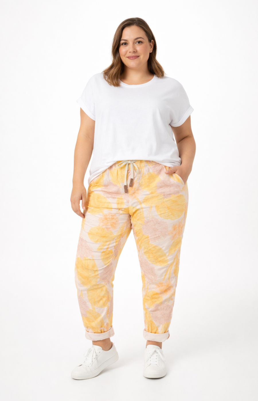 Woman wearing a white t-shirt and yellow tie-dye pants on a white background