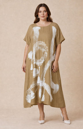 Woman wearing the Giselle Dress in Tan, a beige dress with white abstract patterns on a beige background