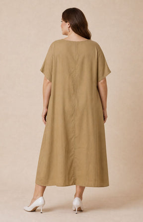 Woman wearing the Giselle Dress in Tan, a beige dress against a beige background