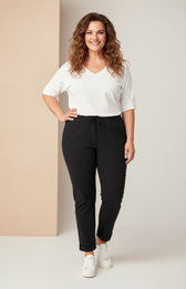 Woman wearing a white top and black pants against a beige background