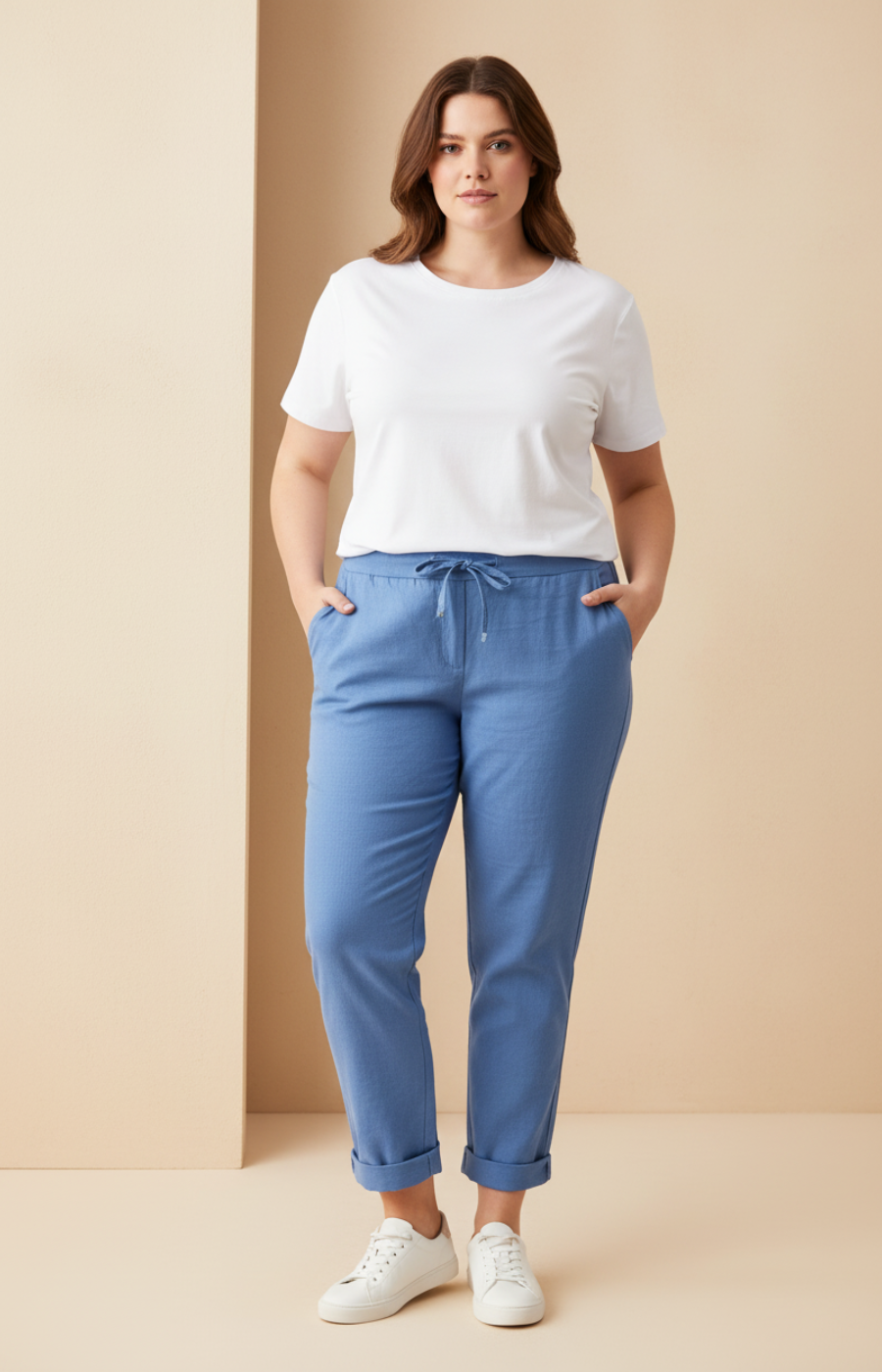 Woman wearing a white t-shirt and blue pants against a beige background