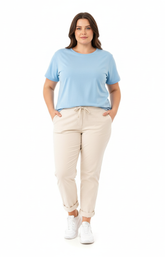 Plus size woman wearing beige pants and a light blue top on a white background