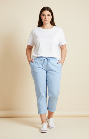Woman wearing a white t-shirt and light blue pants against a beige background