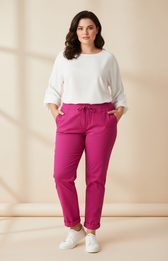 Woman wearing a white top and magenta pants against a beige background