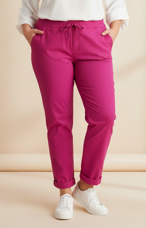 Person wearing magenta pants and white trainers on a beige background