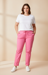 Woman wearing a white t-shirt and pink pants against a beige background