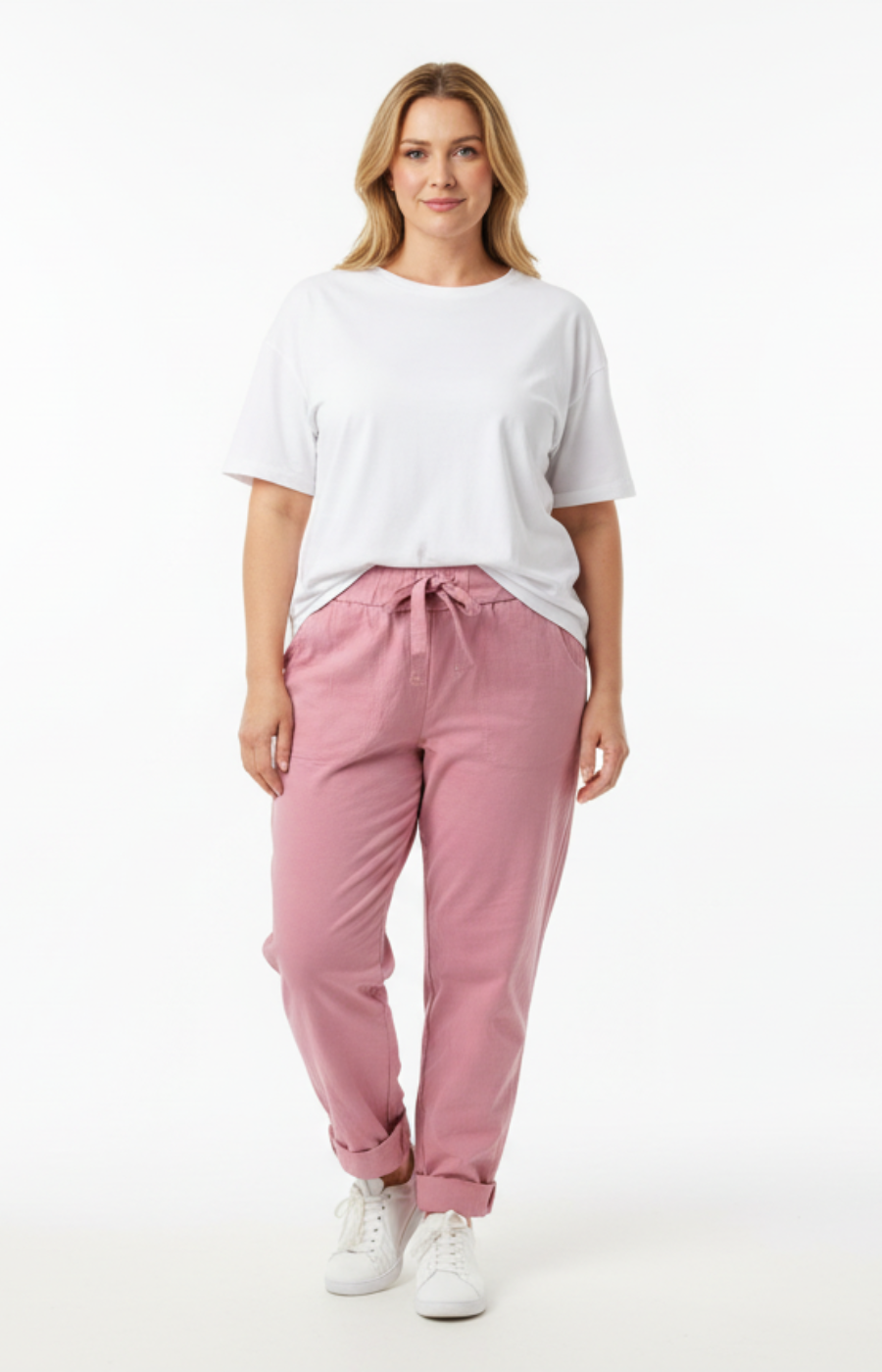 Plus size model wearing a white short-sleeve T-shirt and pink elastic waist trousers with tie belt and rolled cuffs, styled with white runners.