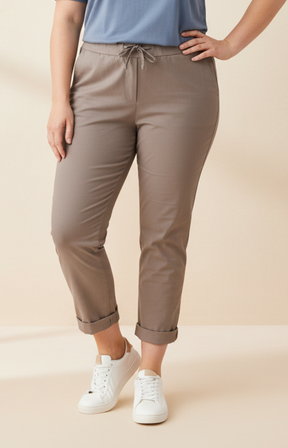 Woman wearing a blue t-shirt and taupe pants on a beige background