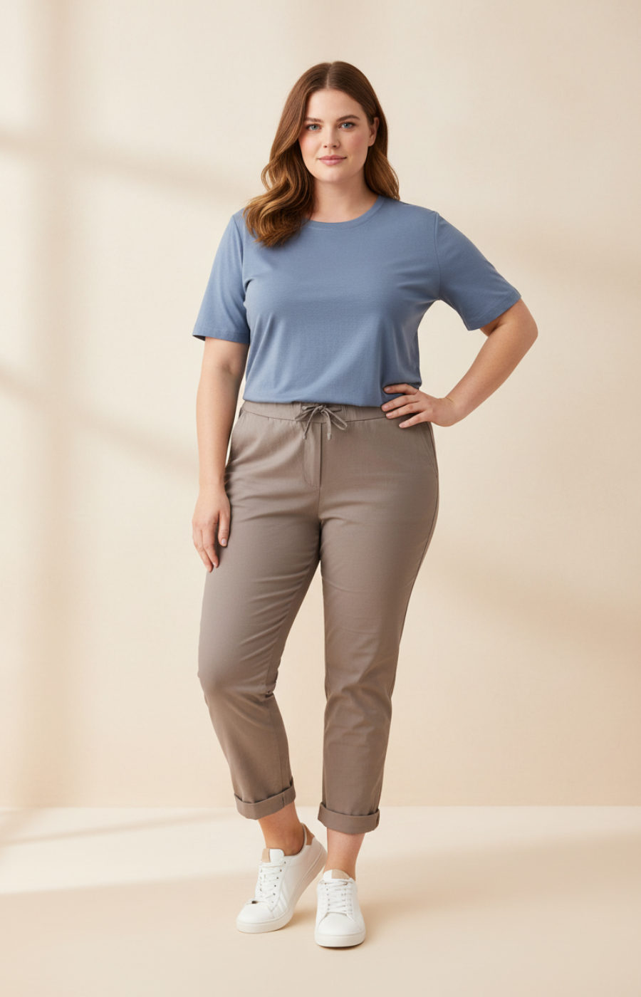 Woman wearing a blue t-shirt and taupe pants on a beige background
