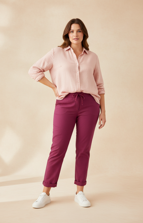 Woman wearing a light pink shirt and wine pants on a beige background
