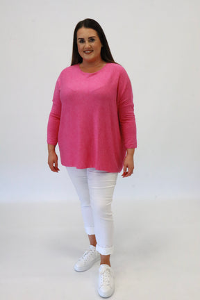 Woman wearing a pink sweater and white pants on a white background