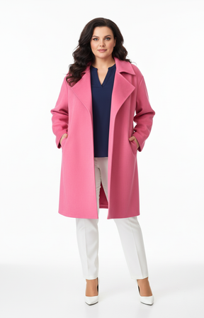 Woman wearing a pink coat over a navy top and white pants on a white background