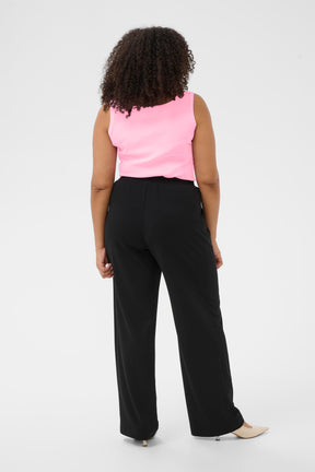 Person wearing a pink sleeveless top and black pants on a white background