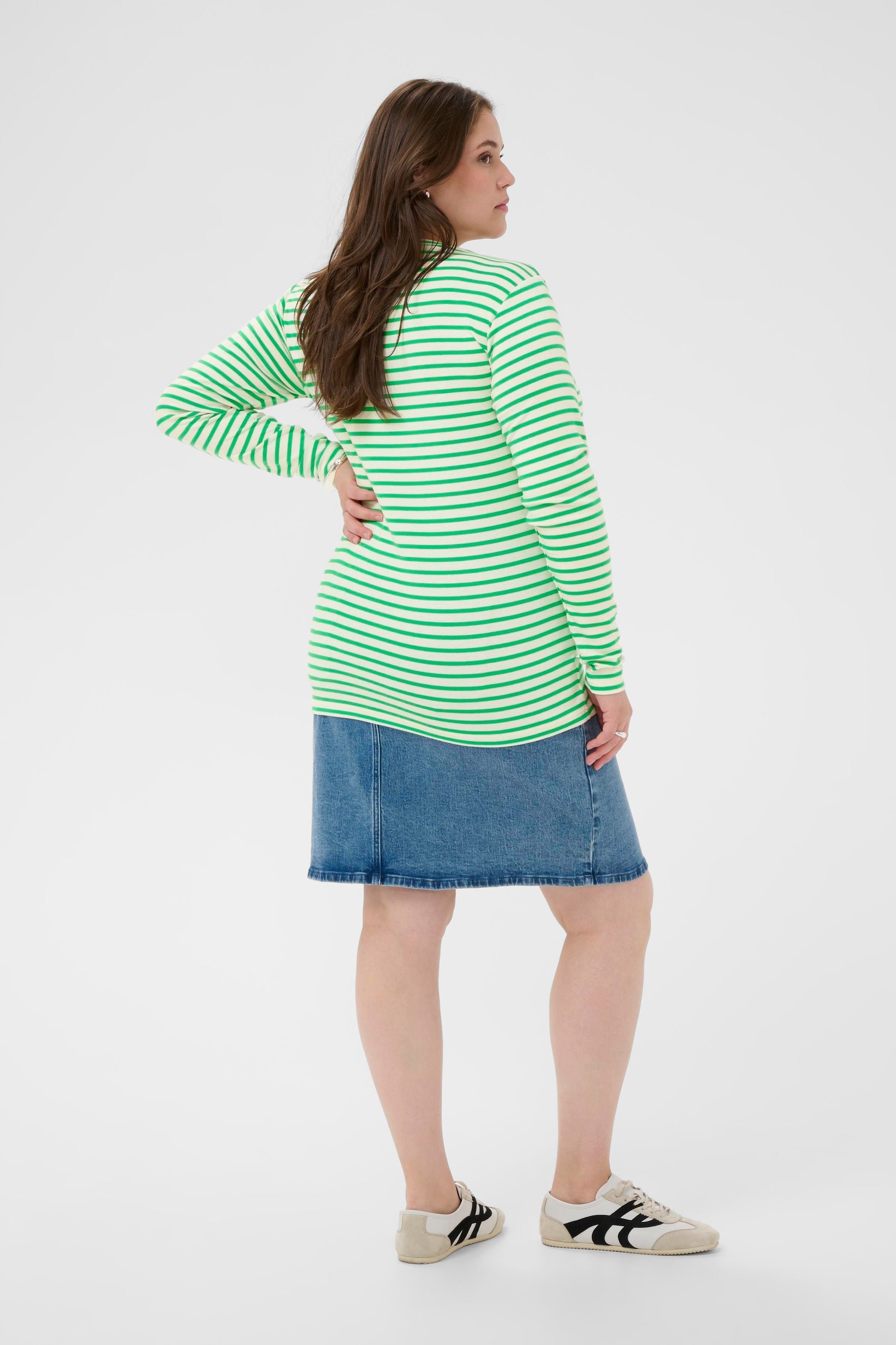 Woman wearing a green and white striped shirt and denim skirt on a white background 