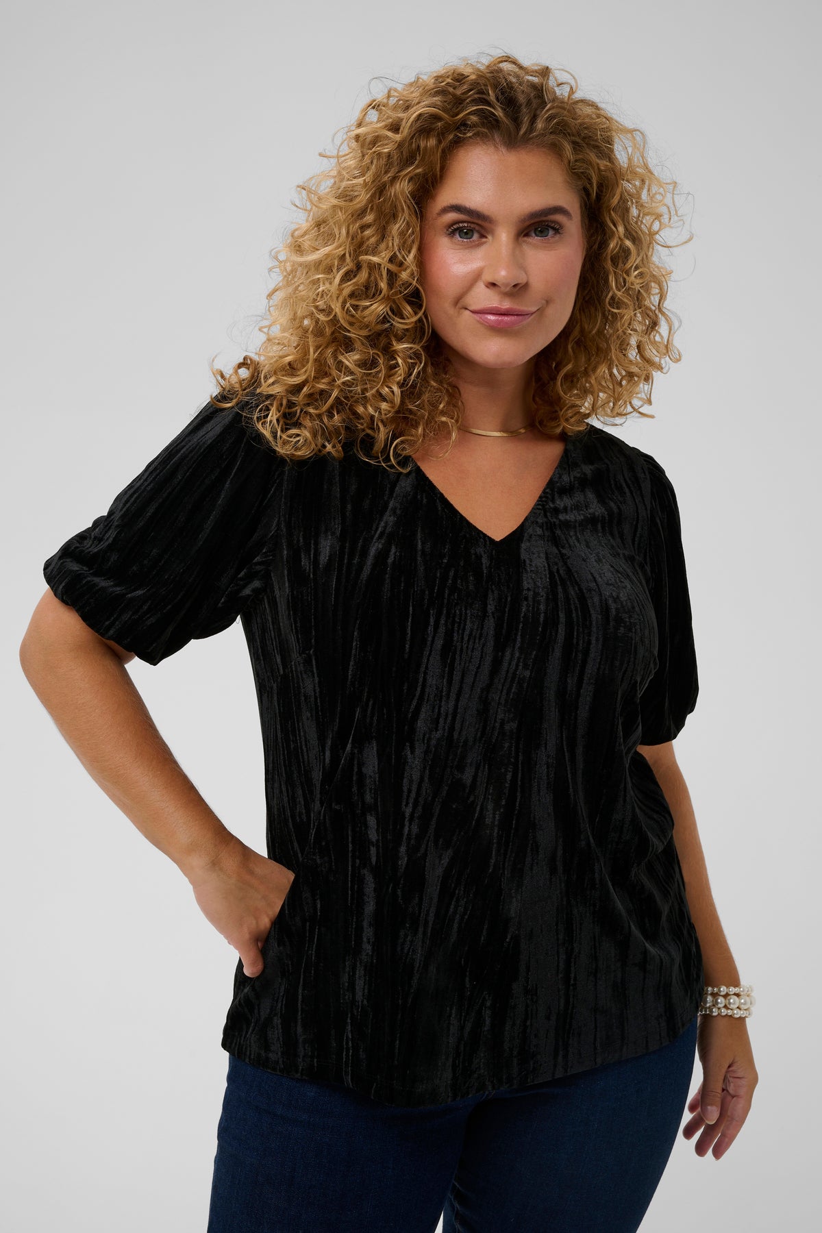 Woman wearing a black textured blouse against a plain background