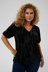 Woman wearing a black textured blouse against a plain background