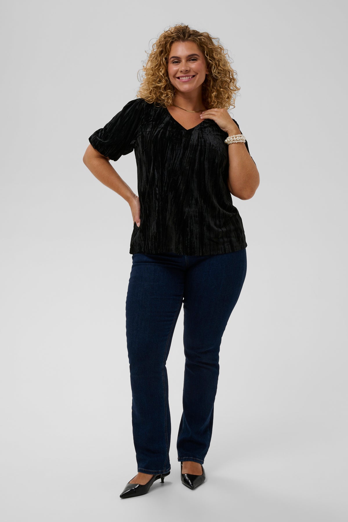 Woman wearing a black top and blue jeans on a white background