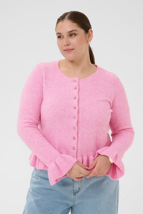 Woman wearing a pink cardigan with long sleeves with ruffled detailing on the cuffs and hem on a white background