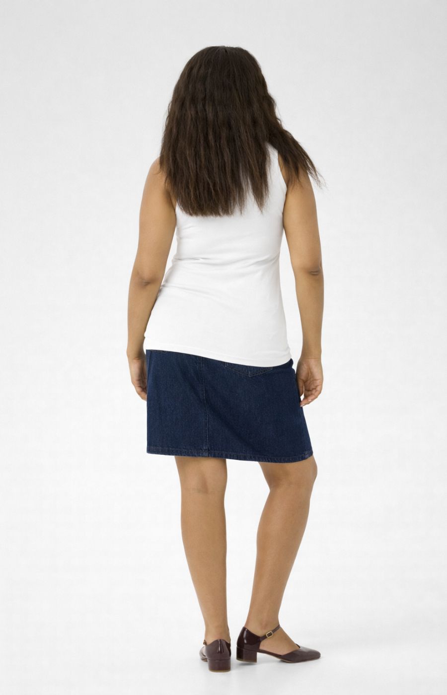 Person wearing a white vest top and navy skirt on a white background