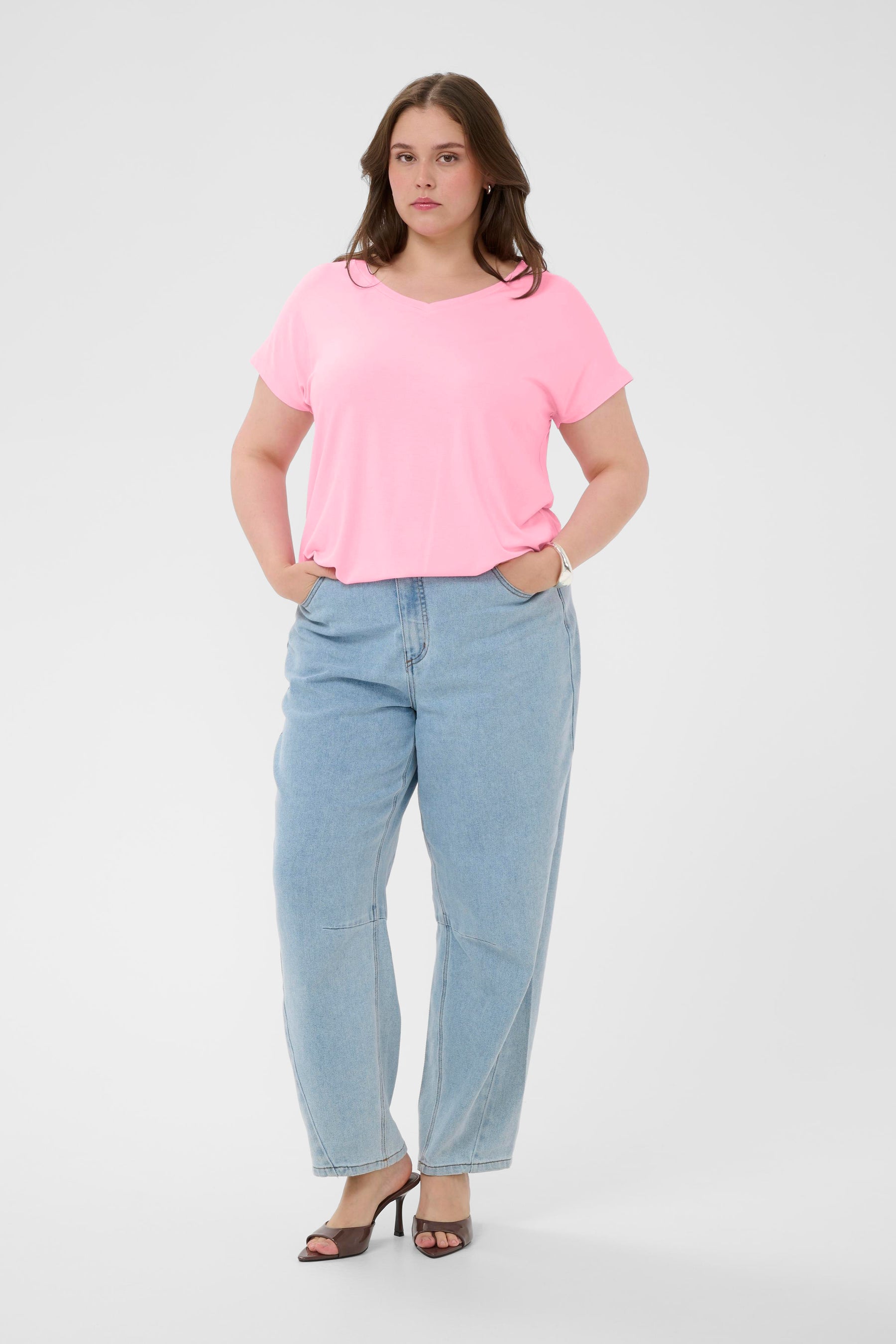 Woman wearing a pink t-shirt and light blue jeans on a white background