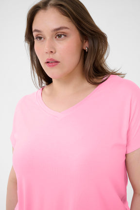 Woman wearing a pink t-shirt with a V neckline and short sleeves against a white background