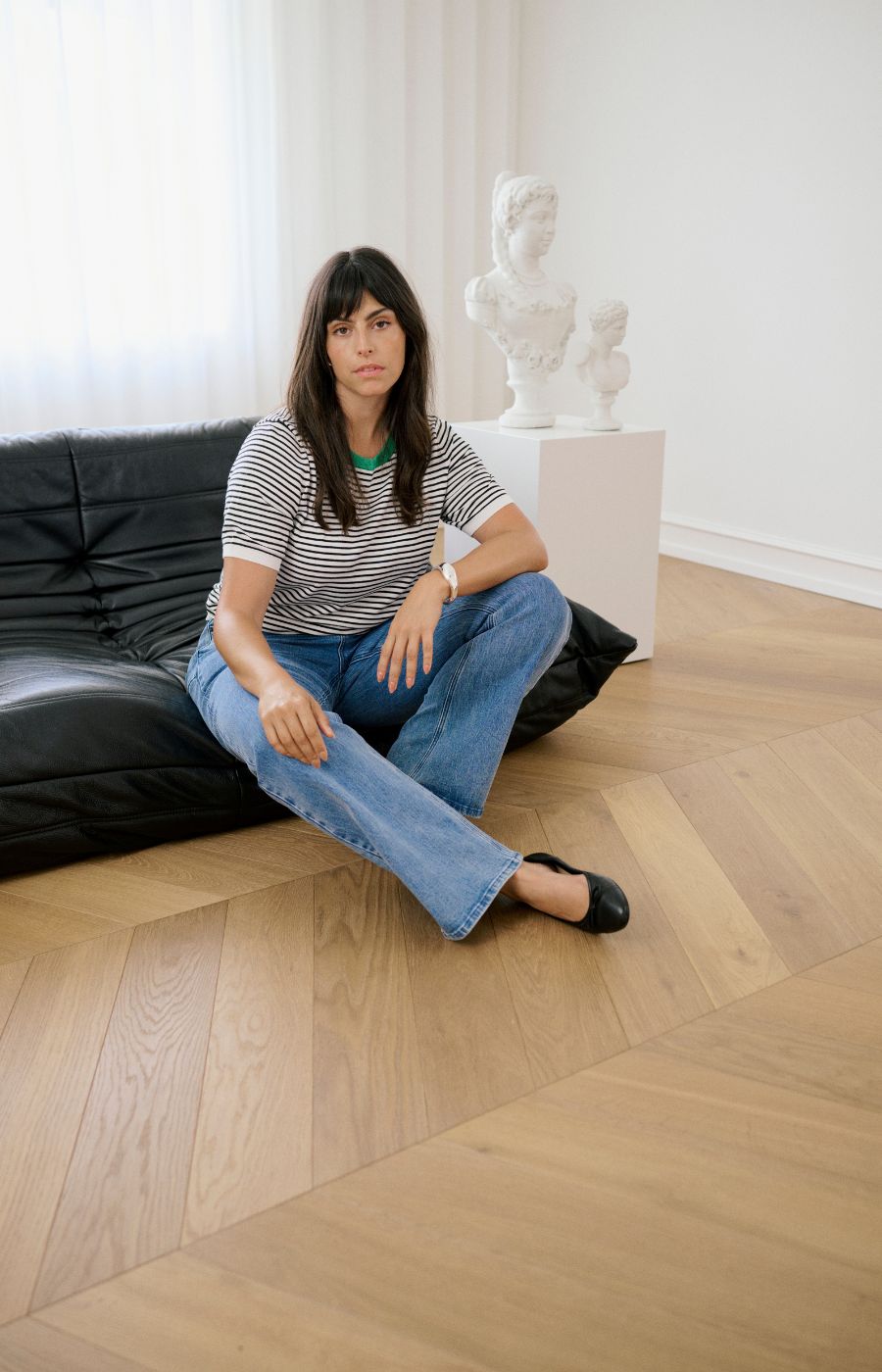 Lady wearing a white top with a black stripe all over and a round green neckline and short sleeves