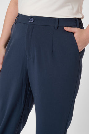 Navy blue pleated trousers worn by a person on a white background