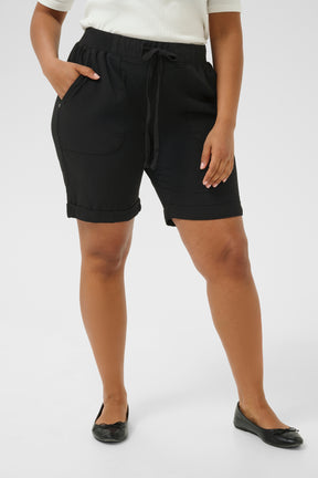 Person wearing black shorts with side pockets, drawstrings in the elasticated waist and a turn up at the end on a white background
