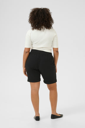 Person wearing black shorts with an elasticated waist band and a white top on a white background
