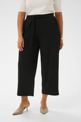 Person wearing black wide leg, ankle grazing trouser that have a built in tie belt with a white top on a white background