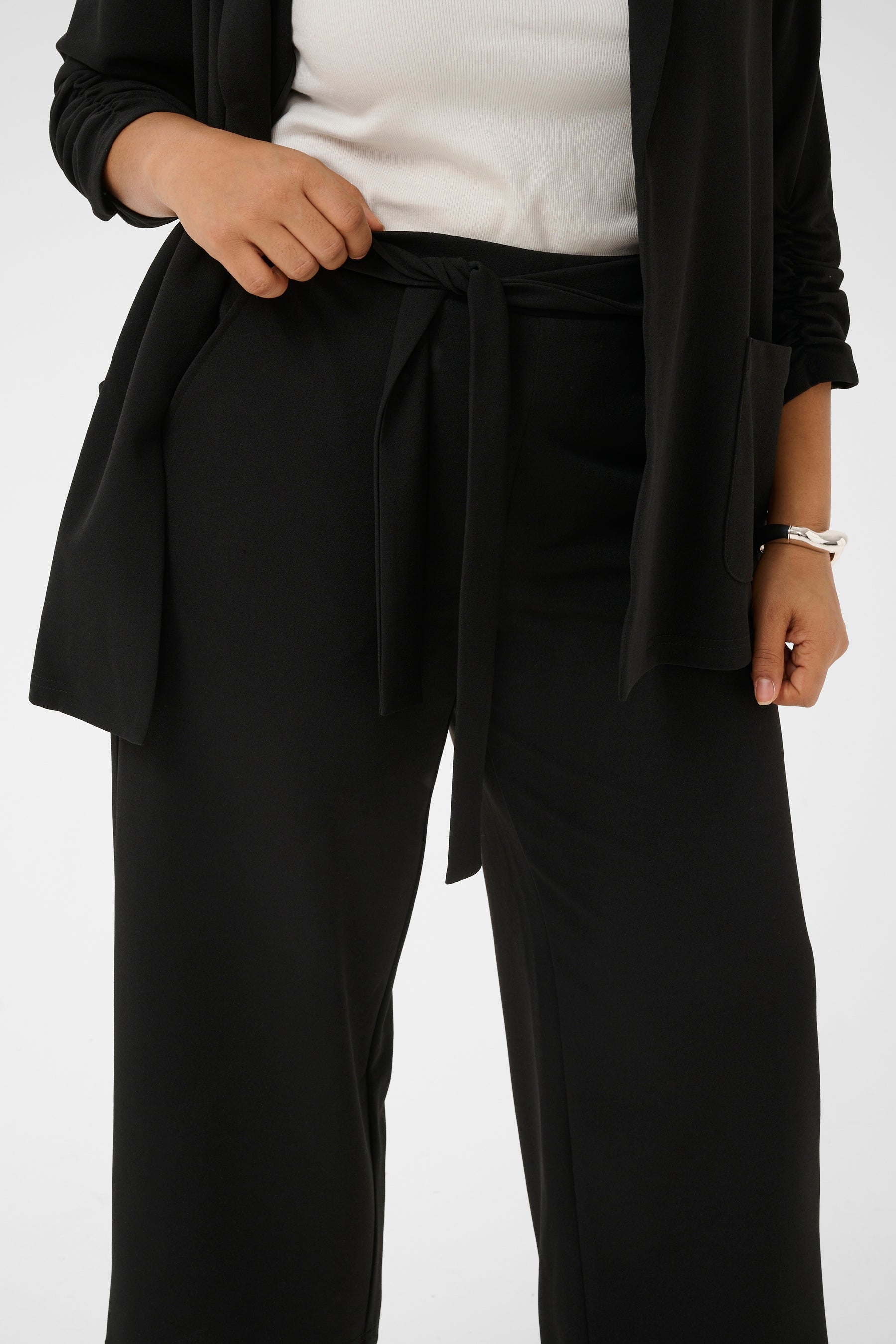 Kaffe Curve Pheolo Trousers in Black, side pockets and a built in tie belt, styled with a white top and matching blazer 