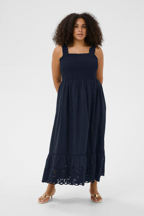 Woman wearing the Kaffe Curve Trudi Dress in Navy, a navy blue dress with lace details on a white background