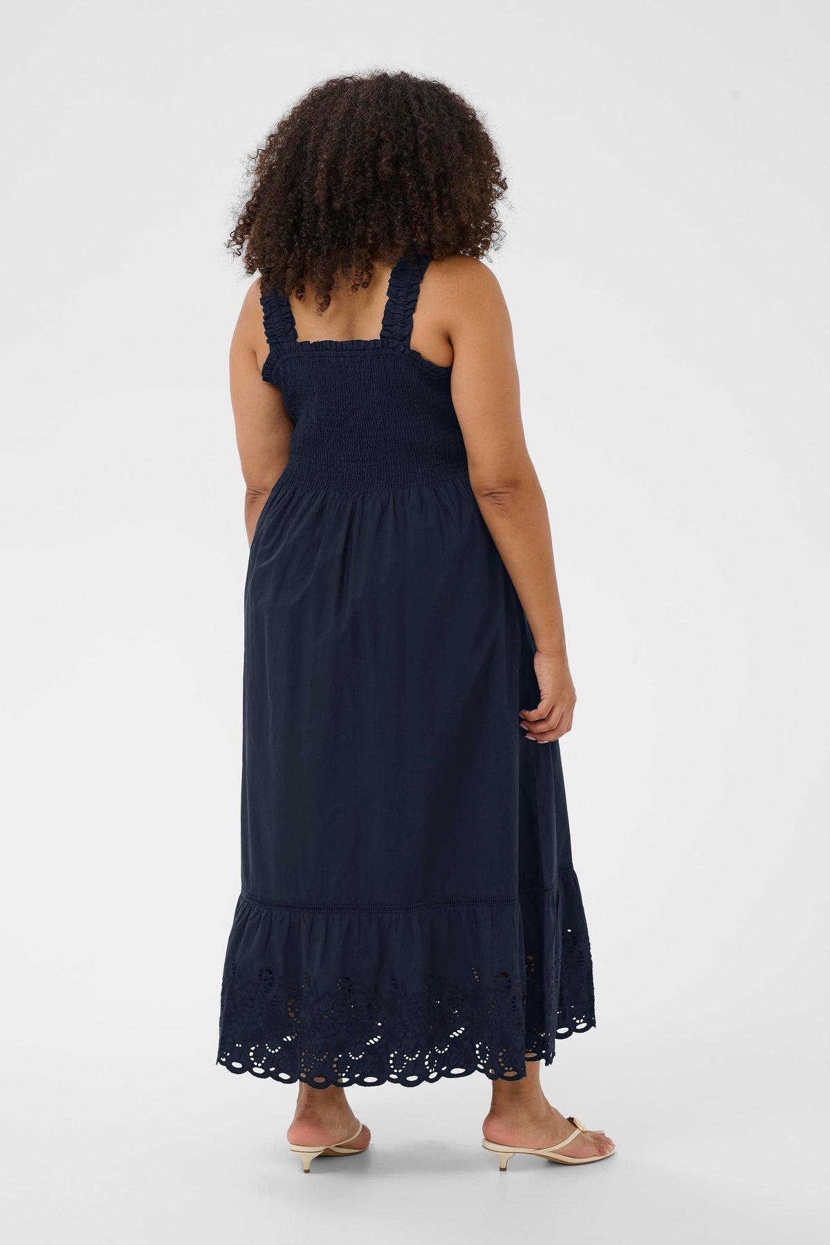 Woman wearing the Kaffe Curve Trudi Dress in Navy, a navy blue dress with lace details on a white background