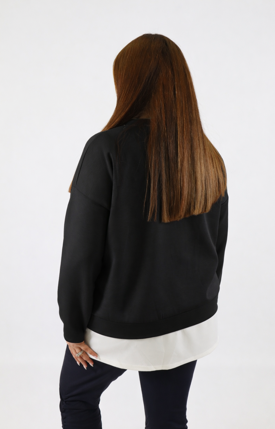 Woman wearing a black sweatshirt with a white trim on a plain background