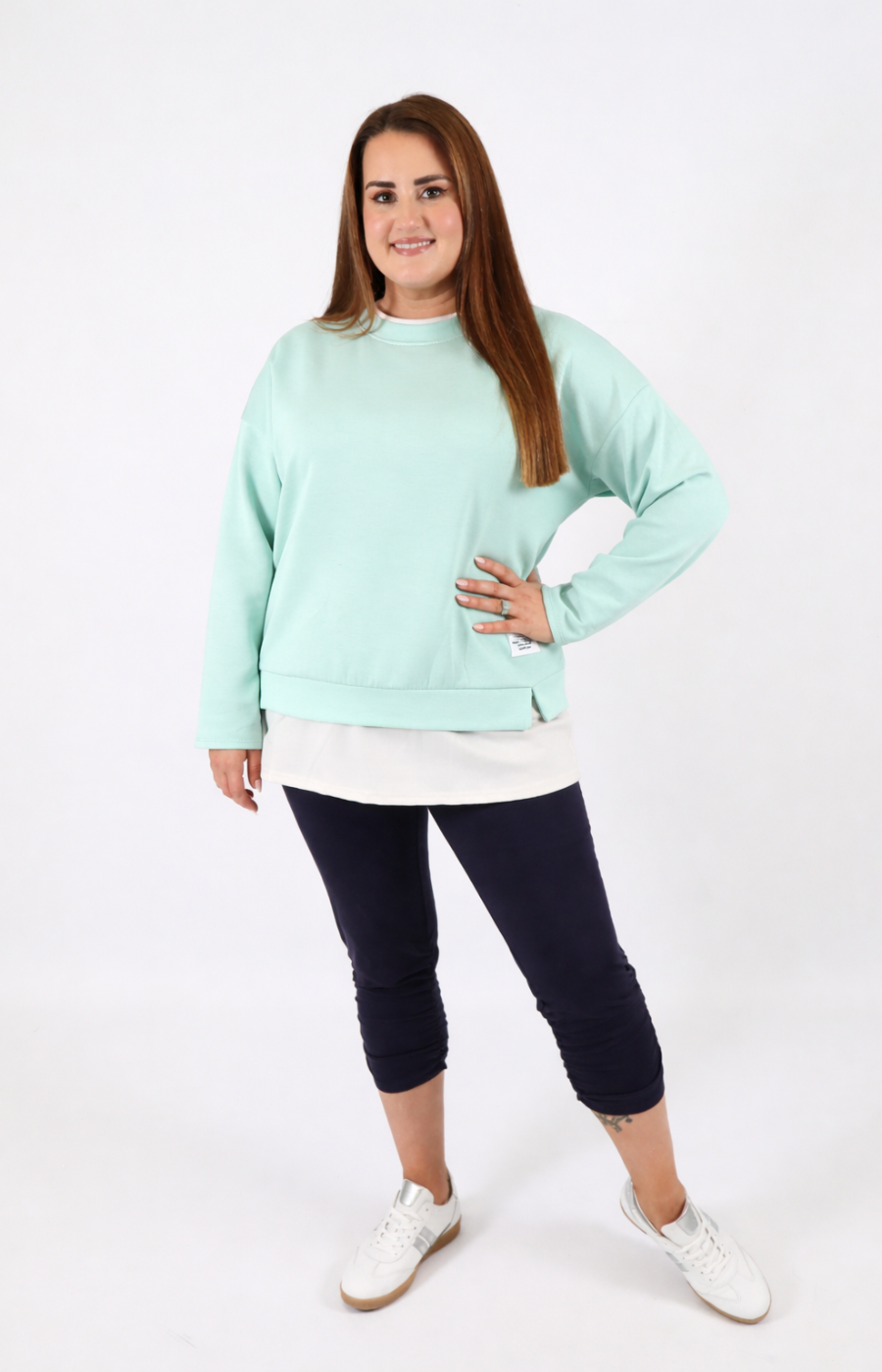 Woman wearing a navy sweatshirt with a white trim on a plain background